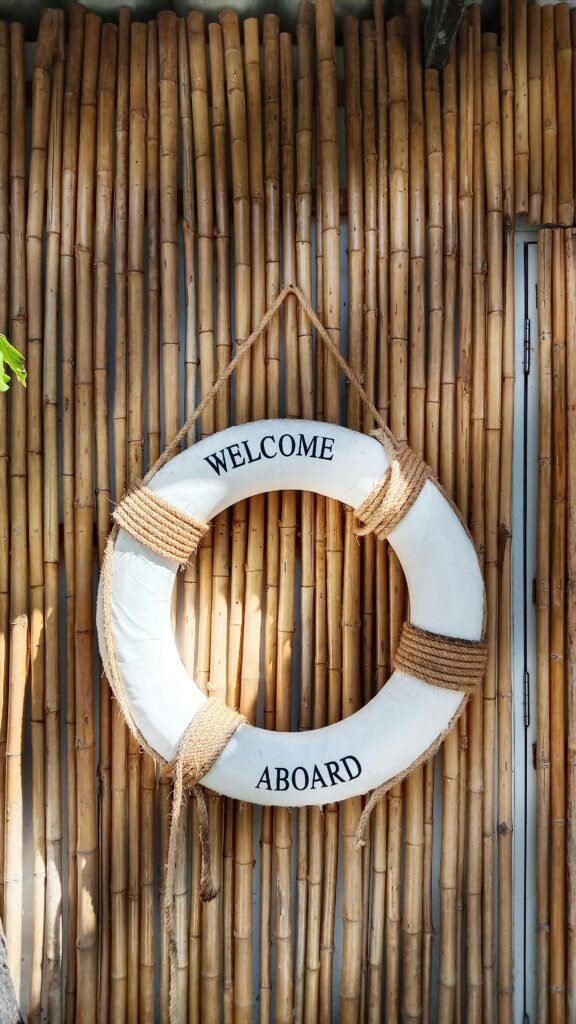 Decorative lifebuoy with 'Welcome Aboard' text hanging on a bamboo wall, evoking a tropical resort vibe.